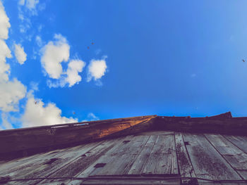 Low angle view of pier amidst buildings against blue sky