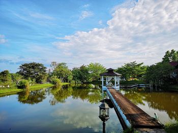 Scenic view of lake by trees and building against sky