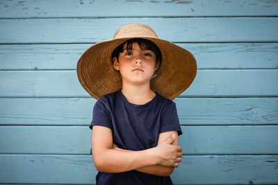 Portrait of very serious child in straw hat with folded arms