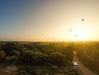 Hot air balloon flying over landscape against sky during sunset