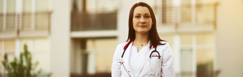 Portrait of young woman standing against building