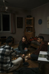 Multiracial male and female friends with ouija board in haunted cabin