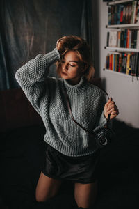 Young woman looking away while standing at home