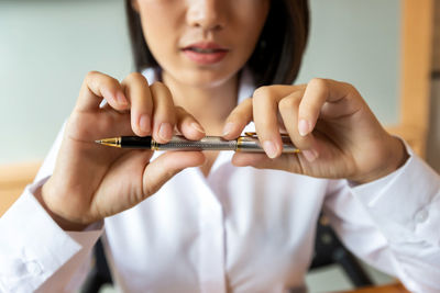 Midsection of woman holding pen