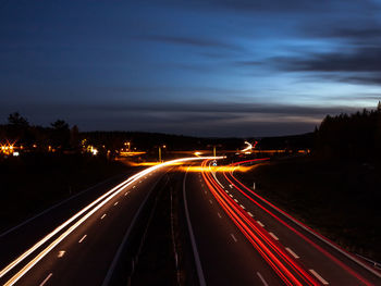 Light trails on road against sky at night