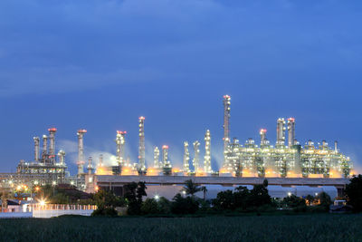 Illuminated factory against sky at night