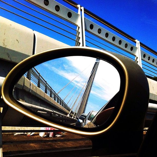 blue, transportation, mode of transport, sky, built structure, reflection, architecture, circle, sunlight, metal, no people, day, land vehicle, low angle view, clear sky, outdoors, railing, close-up, car, glass - material