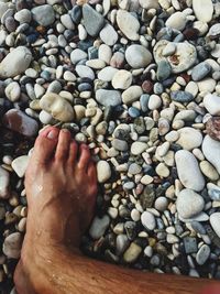 Low section of person on pebbles at beach