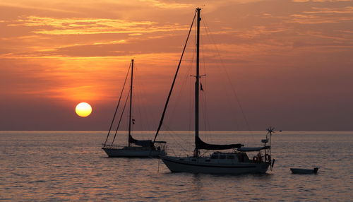 Sailboat sailing on sea against romantic sky at sunset