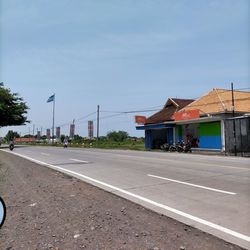 Empty road by buildings against sky