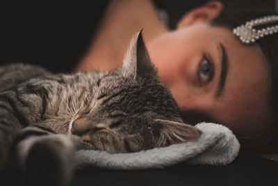 Close-up of cat with girl lying on bed