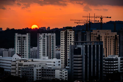 Buildings in city against orange sky