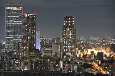 Illuminated buildings in city against sky at night