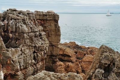 Rock formations by sea against sky