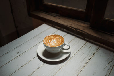 Latte art coffee on wooden table in coffee shop