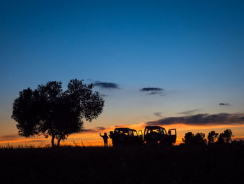 Silhouette trees on field against sky during sunset