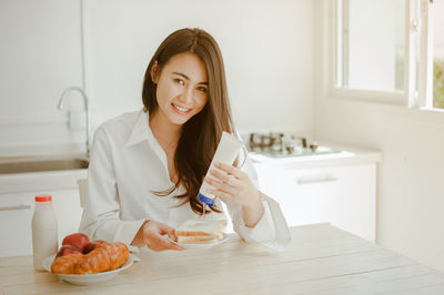 Portrait of a smiling young woman holding food at home