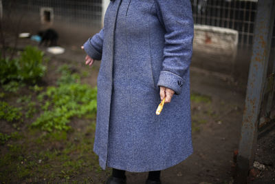 Grandma in an old coat. a woman stands on the street. an old woman in russia fed cats. person