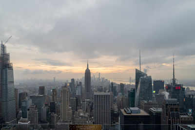 Modern buildings in city against cloudy sky