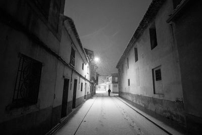 Narrow street amidst buildings in city at night