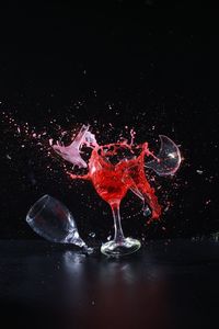 Close-up of water splashing on glass against black background