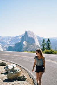 Woman walking on mountain against sky