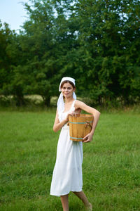 Young woman using mobile phone while standing on field