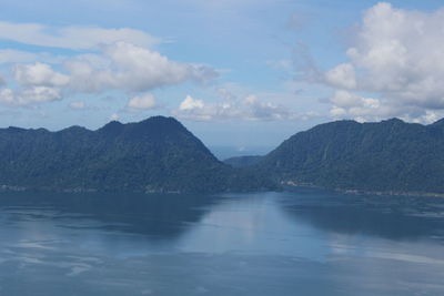 Scenic view of sea by mountains against sky