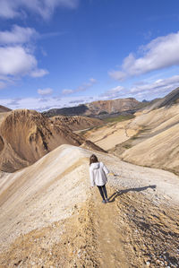 Rear view of man walking on landscape against sky