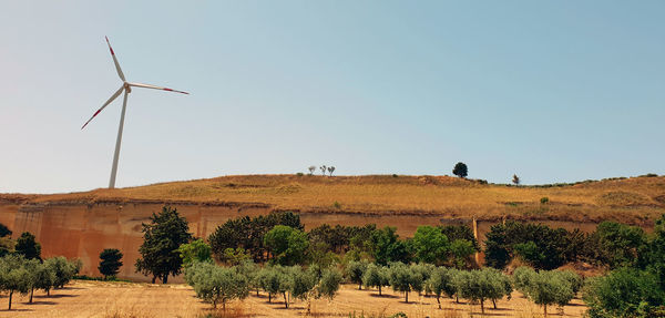 Wind turbines on field against clear sky