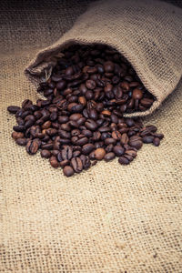 High angle view of coffee beans falling from burlap 