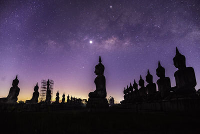 Silhouette temple against building at night