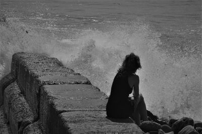 Woman sitting on beach by sea