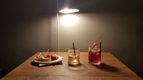 Wine glasses on table against illuminated lights