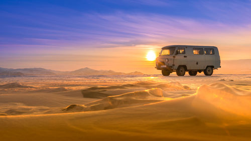 Van on desert against sky during winter