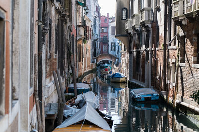 Boats moored in canal amidst buildings in city