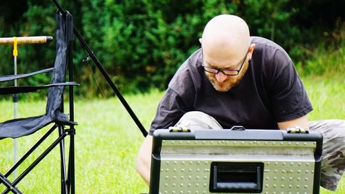 Man looking down by briefcase at grassy field