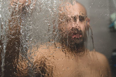 Close-up portrait of wet glass window