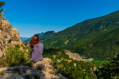 Rear view of woman looking at mountains against blue sky