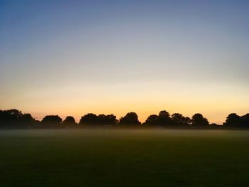 Scenic view of field against clear sky during sunset