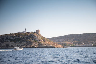 Lighthouse by sea against clear sky