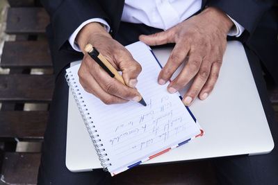 Businessman writing notes in notebook, close-up