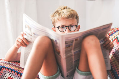 Boy reading newspaper at home