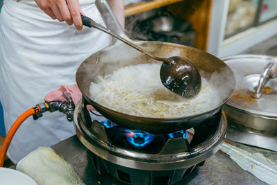 Cropped image of a person preparing  ramen broth