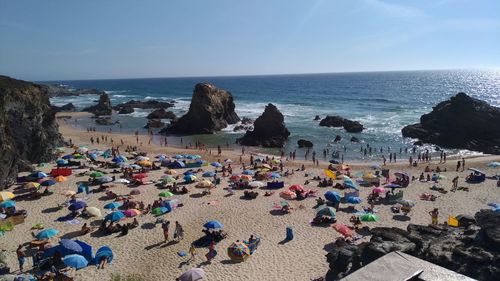 Group of people on rock by sea against sky