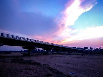 Train on bridge against sky during sunset