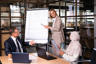 Side view of woman using digital tablet while standing in office