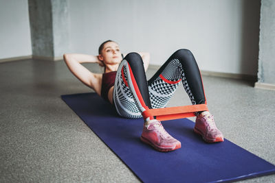Young woman exercising while lying on mat