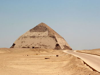 Empty road leading towards pyramid against clear sky