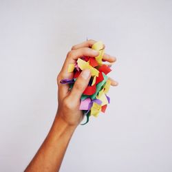 Cropped image of hand holding paper over white background